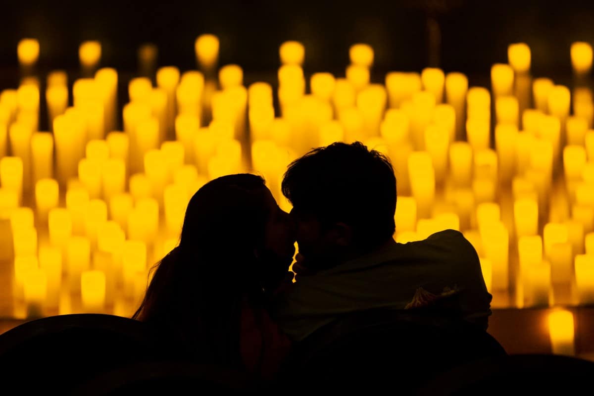 A silhouette of a couple kissing with a sea of candles in the background