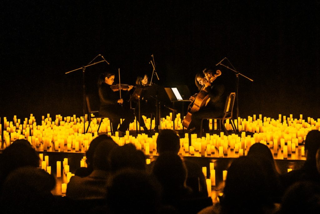 A string quartet performing on a raised stage with the silhouette of audience members on the front