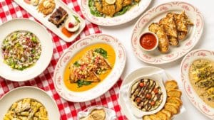 Plates of Italian dishes and desserts in a red tablecloth at Maggiano's.