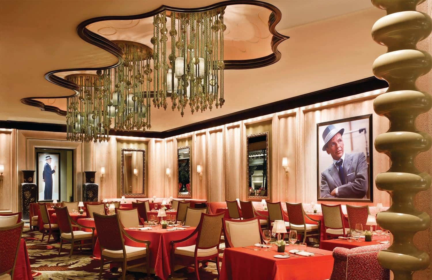 The luxurious red and gold interior of Sinatra with a photo of Sinatra on the wall. 