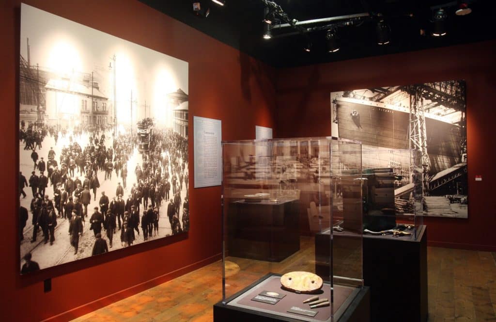 Large-scale photos of people boarding the Titanic alongside artifacts at Titanic: The Artifact Exhibition Las Vegas.