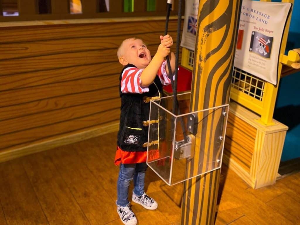 A little boy pulls the mast on a fake ship at DISCOVERY Children's Museum.