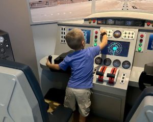 A small child plays with a mock control panel for an airplane.