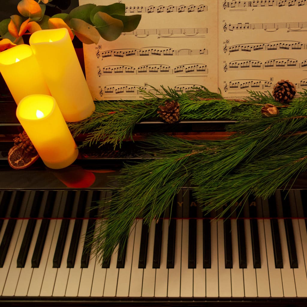 A piano decorated festively with candles.