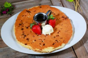 A thick pancake topped with strawberries and cream. 