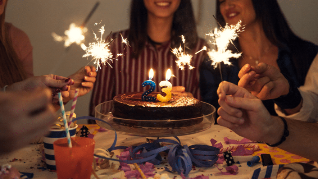 People sitting around a birthday cake with lit up candles