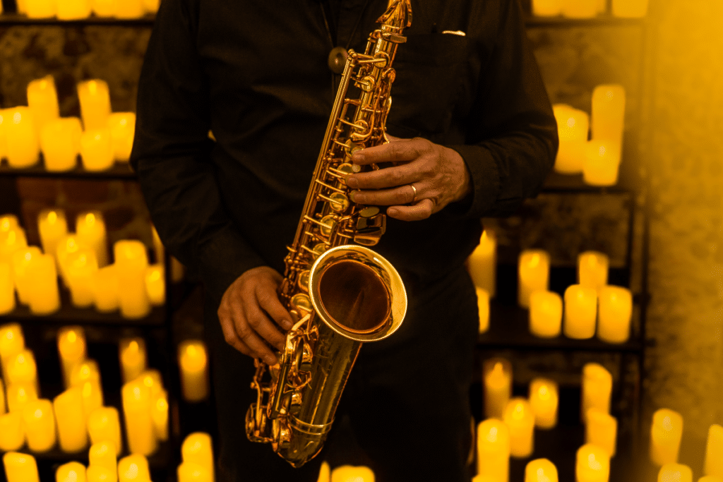 A close up of a musician playing the saxophone with candles in the background