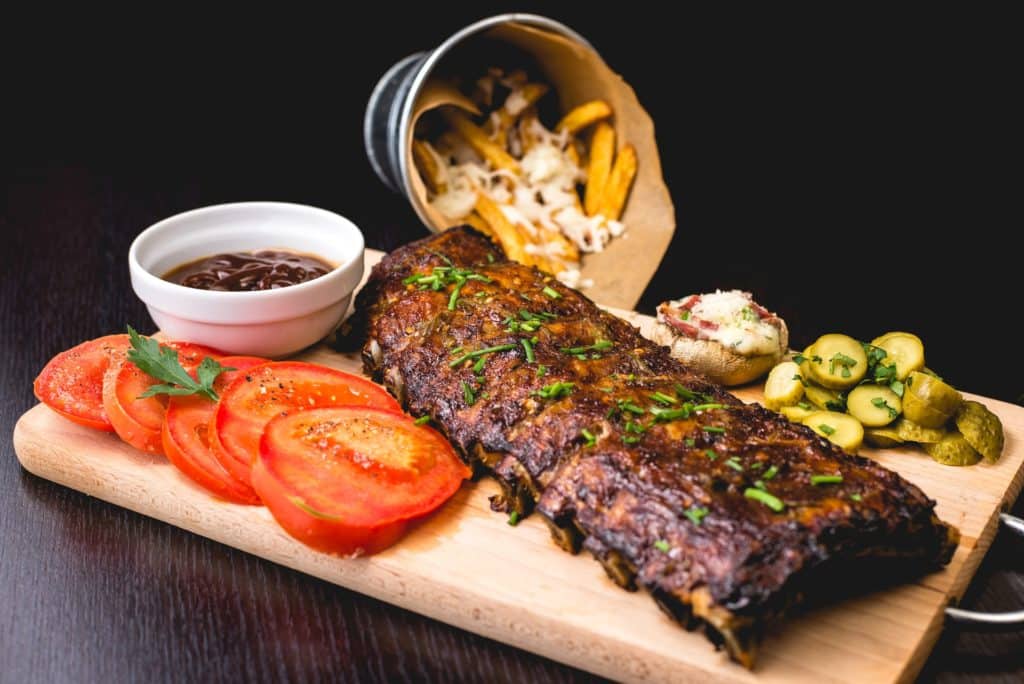 A plate of ribs with slice tomato and ribs at a restaurant. 