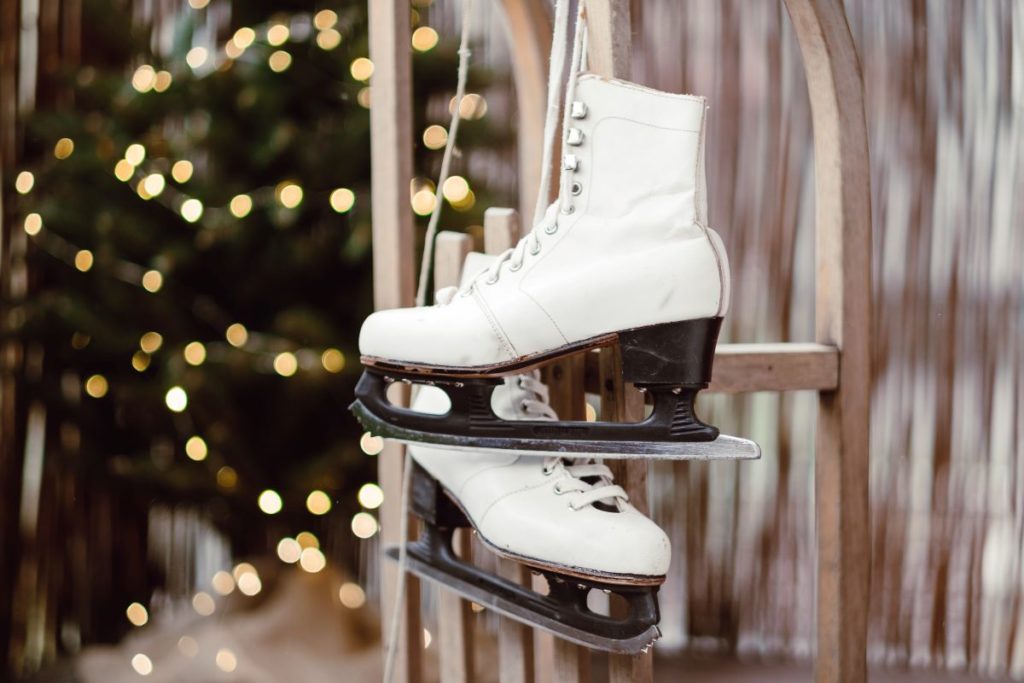 Ice skates hanging in front of a Christmas tree.