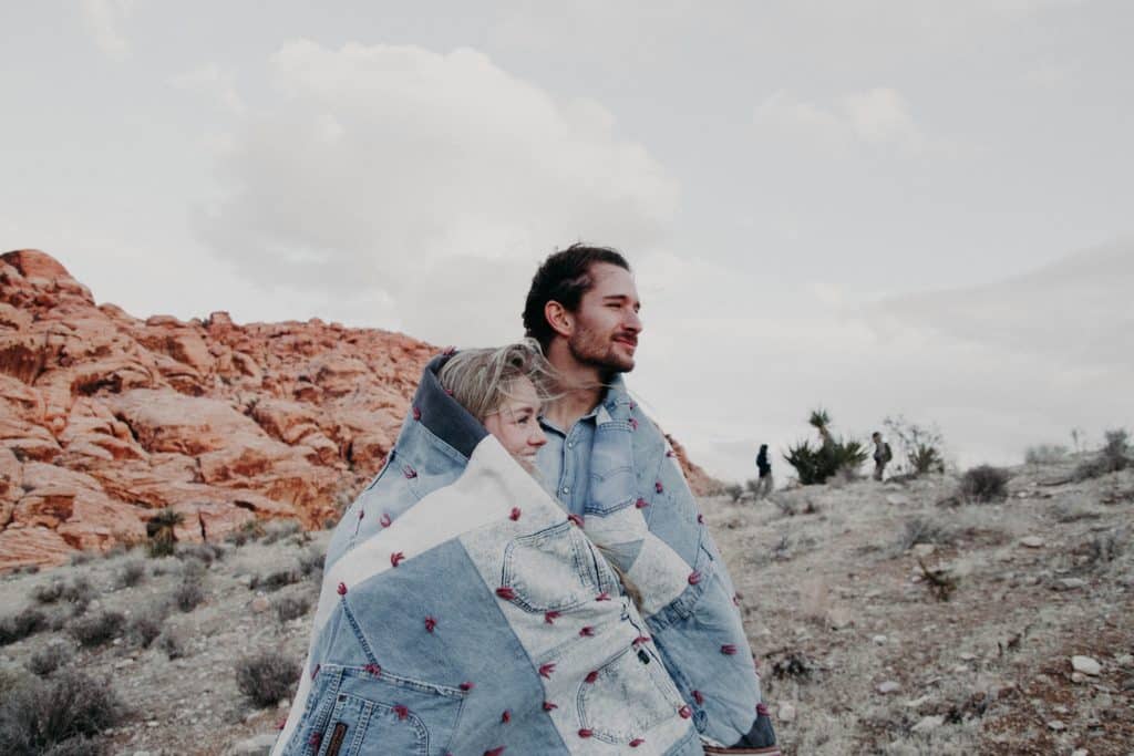A couple sit in Red Rock Conservation area, wrapped in a blanket.